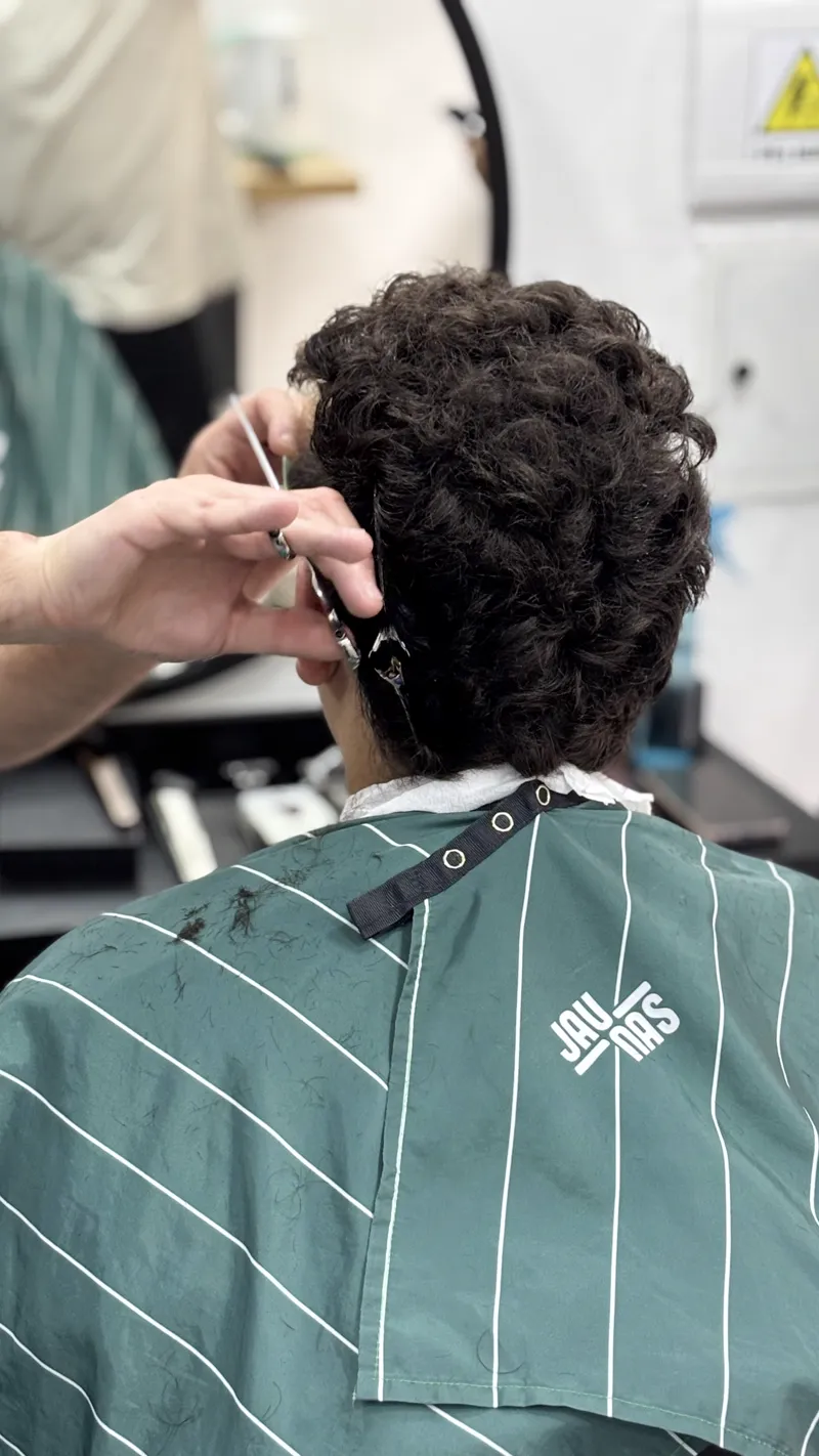 Corte de pelo rizado visto de espaldas, con la capa verde de Jaunas