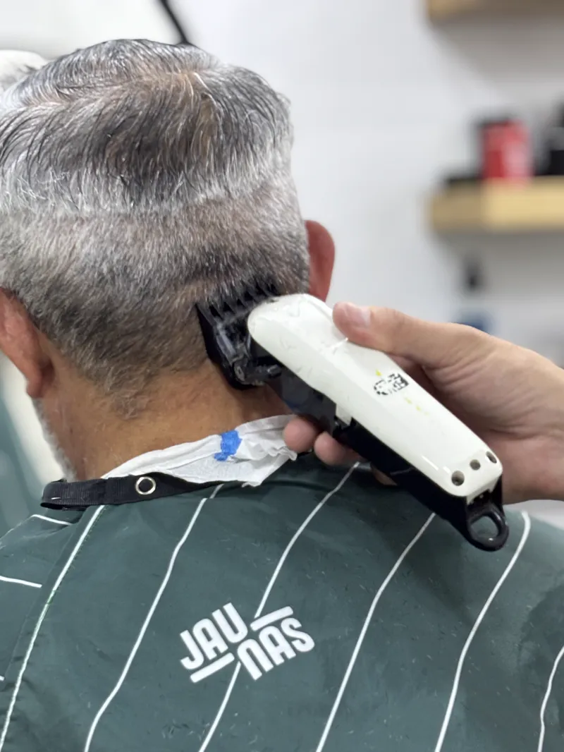 Terminación del corte con máquina en la nuca de un cliente de pelo canoso